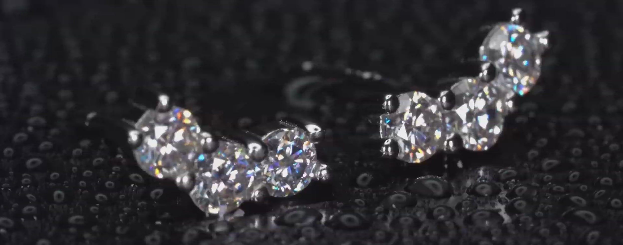 Echte Videoaufnahme von Moissanite Ohrsteckern mit 3 Steinen in Klammerform im echten Licht. Intensives IRL Funkeln mit starken Lichtreflexen und diamantähnlicher Brillanz bei jeder Bewegung. 925 Silber & 18K Weißgold Ohrstecker mit luxuriösem Glanz für Alltag und besondere Momente.