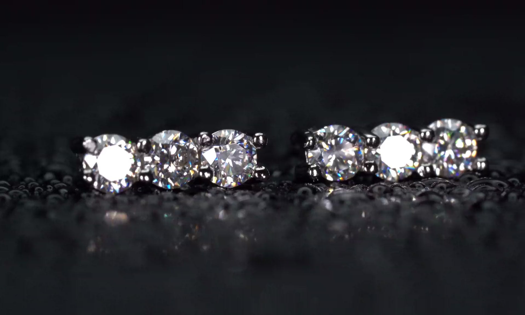 Video der Moissanite Ohrstecker mit 3 Steinen in gerader Reihe im echten Licht mit dauerhaft starkem Funkeln.