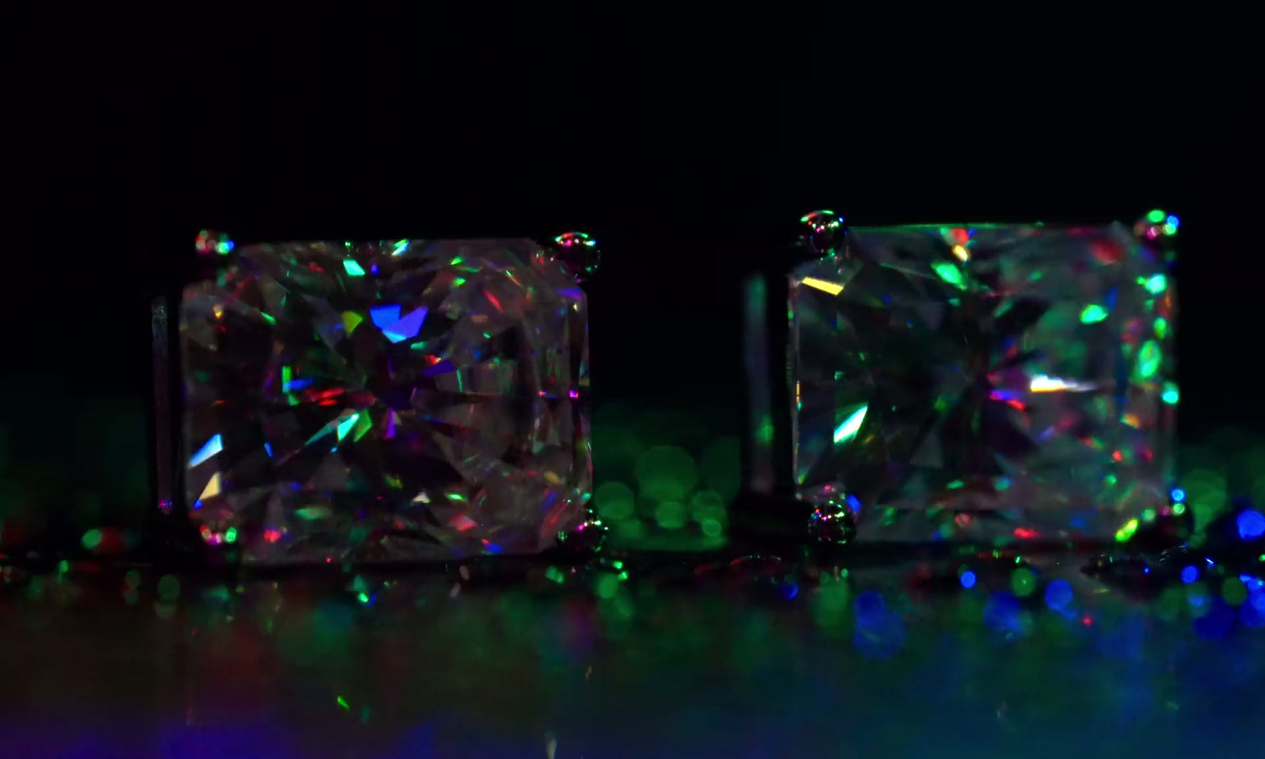 Video der quadratischen Moissanite Ohrstecker im Radiantschliff mit intensivem Feuer und bunten Lichtreflexen unter RGB-Beleuchtung.