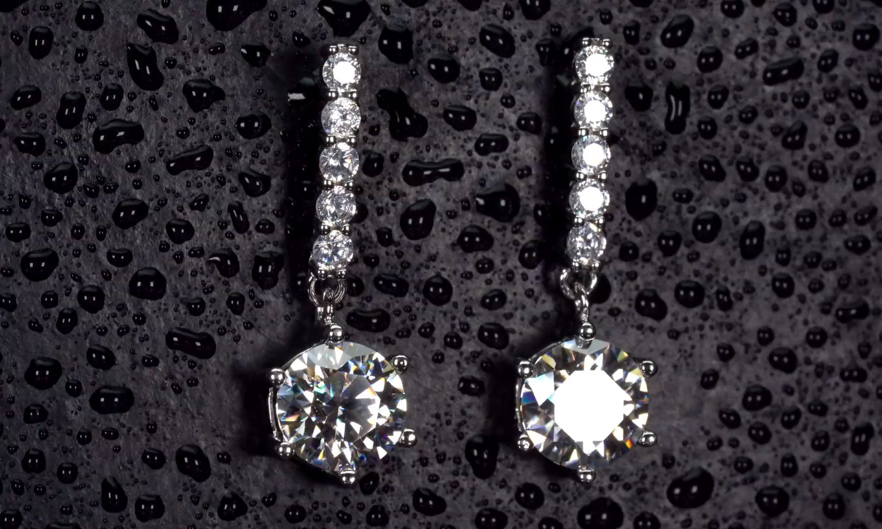 Echte Video Drehung von 1ct Moissanite Ohrsteckern mit beweglichem Anhänger im echten Licht. Extrem intensives Funkeln stärker als bei Diamanten mit sichtbaren Lichtreflexen bei jeder Bewegung. 925 Silber & 18K Weißgold Ohrstecker mit diamantähnlicher Härte für luxuriösen Glanz im Alltag.