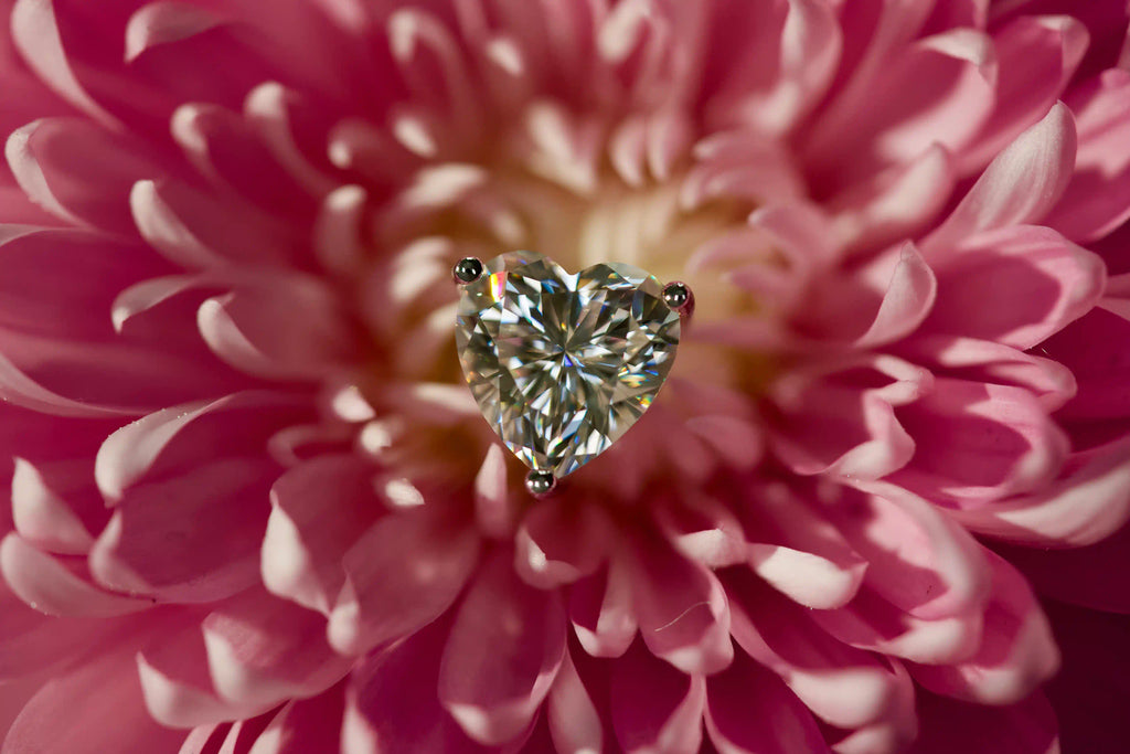 Romantische Herzschliff Moissanite Ohrstecker als Geschenk für Frauen im echten Licht fotografiert – extrem starkes Funkeln stärker als Diamant auf rosa Blüte.
