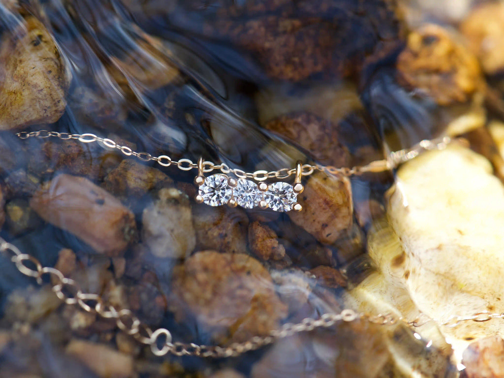 Moissanite Kette in Roségold mit drei 3 mm Brillanten in Reihenfassung unter Wasser im Bach fotografiert – echte Fotos mit starkem diamantähnlichem Funkeln im natürlichen Licht